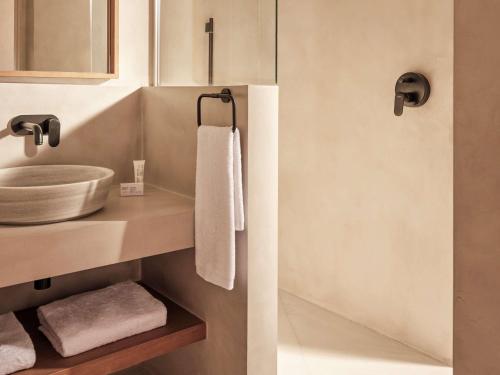 a bathroom with a sink and a counter with towels at Mondrian Ibiza in Cala Llonga