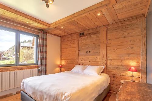 una camera con un letto su una parete in legno di Six-Deniers a Les Gets