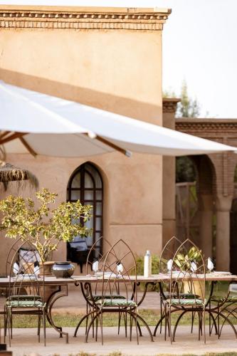 a table and chairs with a white umbrella at Villa Serena Marrakech - Maison d'hôtes in Marrakech
