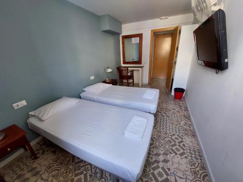 a room with two beds and a tv on the wall at Alberg Sants Bcn in Barcelona