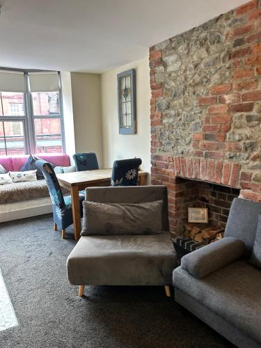 a living room with a couch and a brick fireplace at Cadwgan House in Rhayader