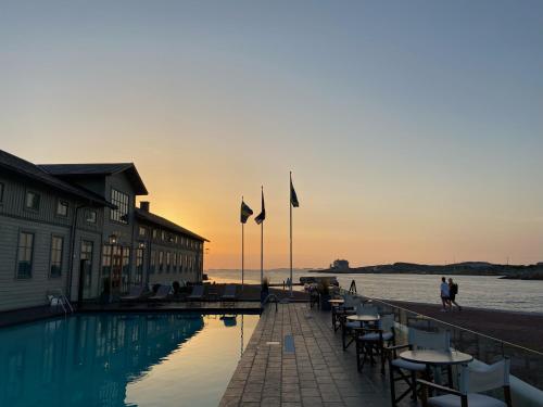 a pool with tables and chairs next to the water at Marstrands Kurhotell in Marstrand