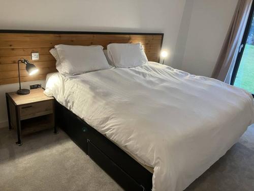 uma cama grande com uma cabeceira de madeira e uma mesa em Otters Cove, Middleton Hall Estate em Belford