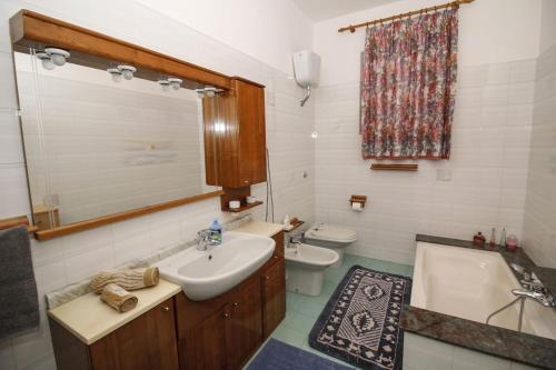 een badkamer met een wastafel, een bad en een toilet bij La casa di Carlo in SantʼAntìoco
