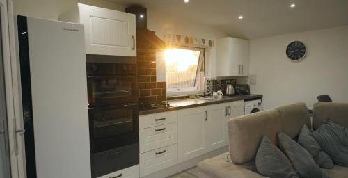 uma cozinha com um sofá e um fogão forno superior em Lovely 1-Bed Lodge in Haverfordwest with views em Haverfordwest