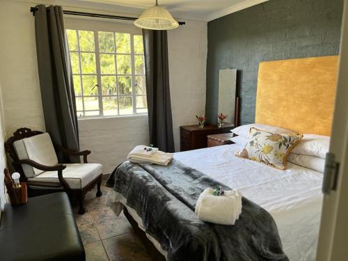 ein Schlafzimmer mit einem Bett, einem Stuhl und einem Fenster in der Unterkunft Bekkersvlei - Die Huis in Haenertsburg