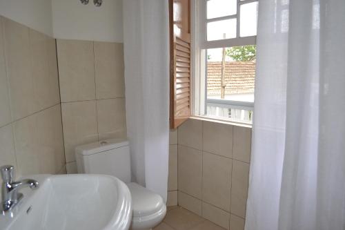 ein Bad mit einem WC, einem Waschbecken und einem Fenster in der Unterkunft Hotel POUSADA Brava in Vila Nova Sintra