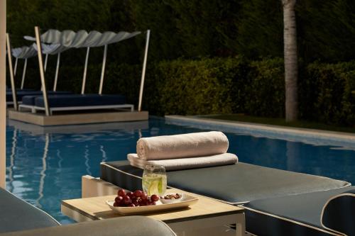 a table with a bowl of fruit next to a pool at Mare Ayia Napa in Ayia Napa