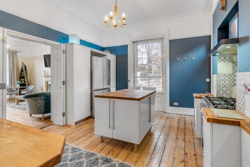 a kitchen with blue walls and a wooden floor at Brooklyn Villa in Norwich