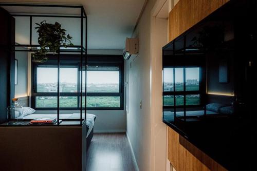 a room with two beds and a large window at Studio contemporâneo no Parque Una com garagem in Pelotas