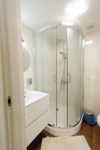 a white bathroom with a shower and a sink at Вілла у горах in Krasnik