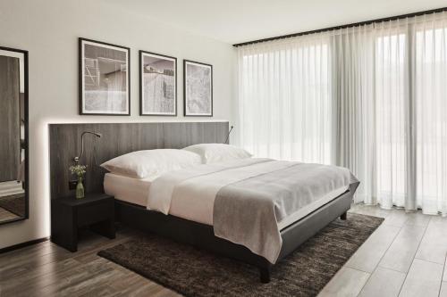 1 dormitorio con 1 cama grande en una habitación con ventanas en THREE POINT Apartments, en Zúrich