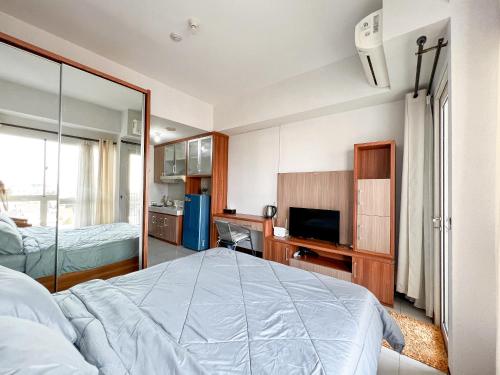 a bedroom with a bed and a television in it at Campus Convenience at Scientia Apartment in Tangerang
