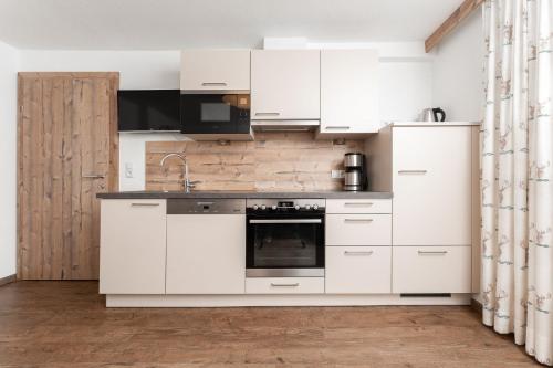 a kitchen with white cabinets and a sink at Haus Margret in Sankt Leonhard im Pitztal