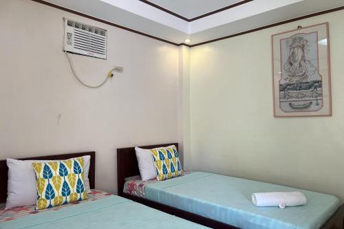 two twin beds in a room with a ceiling at Dinah's Tourist Inn Puerto Princesa in Puerto Princesa City