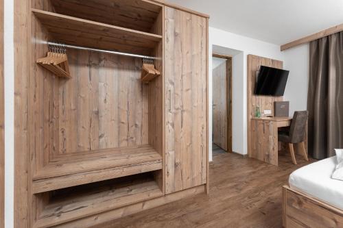 a room with a wooden wall with a bed and a desk at Haus Margret in Sankt Leonhard im Pitztal