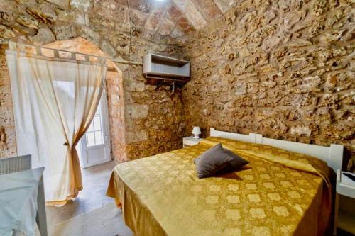 een slaapkamer met een bed en een stenen muur bij Tenuta Rosa Casa Salento Holidays in Taviano