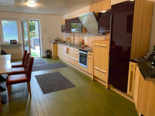 een keuken met houten kasten en een zwarte koelkast bij Gästehaus Rachinger in Pappenheim