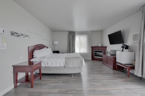 a bedroom with a bed and a desk and a tv at Hôtel et Pavillons Le Petit Manoir du Casino in La Malbaie