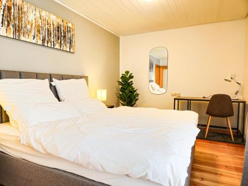 a bedroom with a white bed and a desk at Relax & Business Apartment 122qm mit Balkon, Kamin und Disney+ in Sindelfingen
