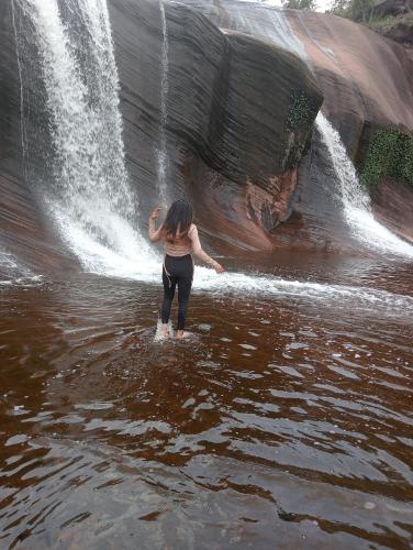 Eine Frau, die vor einem Wasserfall im Wasser steht. in der Unterkunft รี่สอตน้ำตกถ้ำพระ in Ban Non Sung
