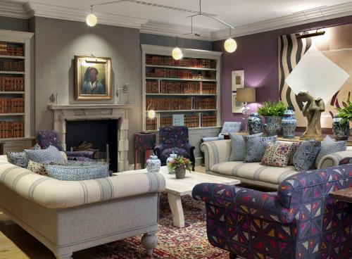 a living room with two couches and a fireplace at Haymarket Hotel, Firmdale Hotels in London