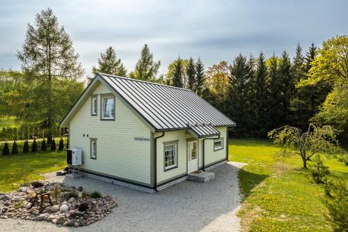 une petite maison sur un terrain de gravier avec des arbres en arrière-plan dans l'établissement Kalakuninga Puhkemaja, à Liimala