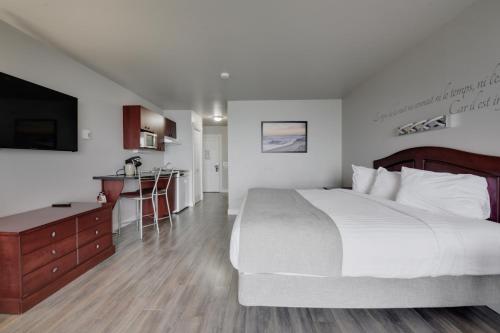 a hotel room with a large bed and a kitchen at Hôtel et Pavillons Le Petit Manoir du Casino in La Malbaie
