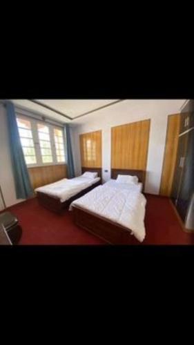 a bedroom with two beds and two windows at Naqcho Paradise Inn Hotel in Skardu