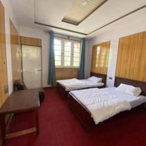 a hotel room with two beds and a desk at Naqcho Paradise Inn Hotel in Skardu