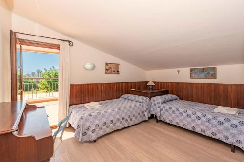 a bedroom with two beds and a table and a window at Villa Camp del Bosch by Sealand Villas in El Port