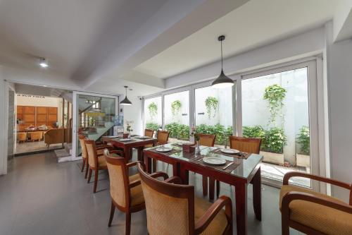 a dining room with tables and chairs and windows at Golden Sunshine Villa Hotel and Travel in Hanoi
