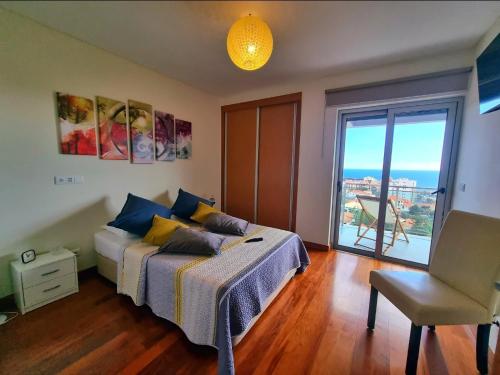 een slaapkamer met een bed en een groot raam bij Apartamento grande familiar con vistas panorámicas al mar y la montaña in Funchal
