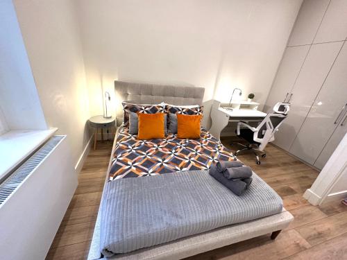 Cette chambre comprend un lit avec des oreillers orange et un bureau. dans l'établissement Cozy Flat in South Kensington, à Londres