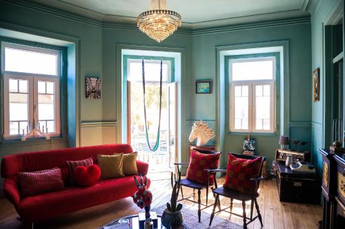 Coruche - A casa do Baloiço في كوروش: غرفة معيشة مع أريكة حمراء وكرسيين