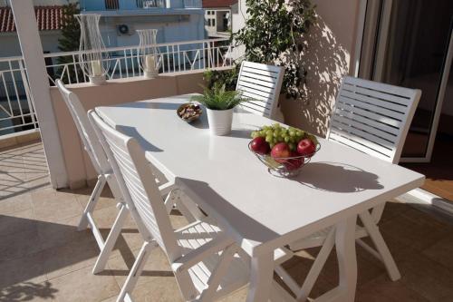 a white table with a bowl of fruit on a balcony at Bozikis House! A cosy apartment in the city centre in Skiathos