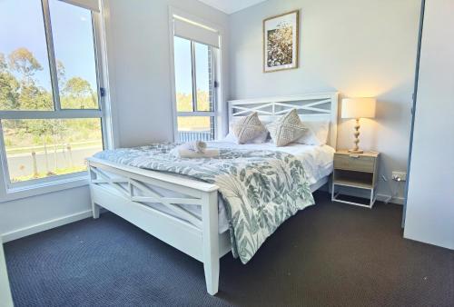 a bedroom with a white bed with a stuffed animal on it at Delightful 2-level home in Bardia in Ingleburn