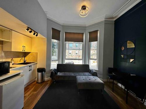 Stylish studio for 3 near Regent’s Park n3 في لندن: غرفة معيشة مع أريكة ومطبخ