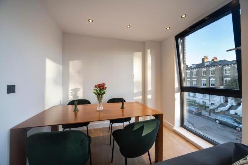 a dining room with a table and chairs and a large window at Bright & Quiet - Spacious Apt with Balcony & Lift in London
