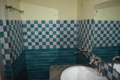 a bathroom with a sink and a checkered wall at LaCliff Nature Home in Dhanaulti