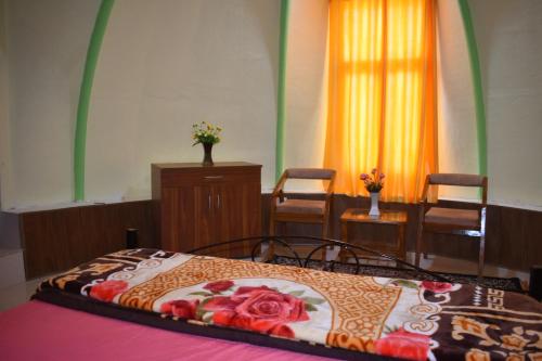 a bedroom with a bed and two chairs and a window at LaCliff Nature Home in Dhanaulti