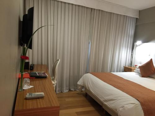 a hotel room with a bed and a desk with a television at Purobaires Hotel Boutique in Buenos Aires