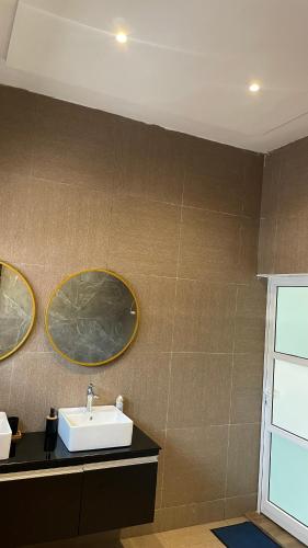 uma casa de banho com um lavatório e dois espelhos na parede em Ara Access em Cotonou