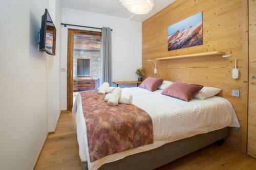 sypialnia z dużym łóżkiem i drewnianą ścianą w obiekcie Echo du Pleney A001 w mieście Morzine