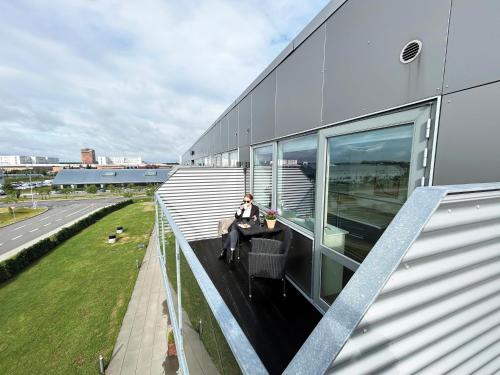 a person sitting at a table on the balcony of a building at athome apartments in Aarhus