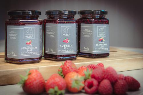 three jars of strawberry jam next to strawberries on a shelf at The Lodges @ Barra Castle in Inverurie