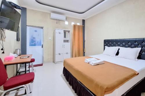 een slaapkamer met een bed, een bureau en een televisie bij Hotel Jelita Mentawai Redpartner in Tua Pejat
