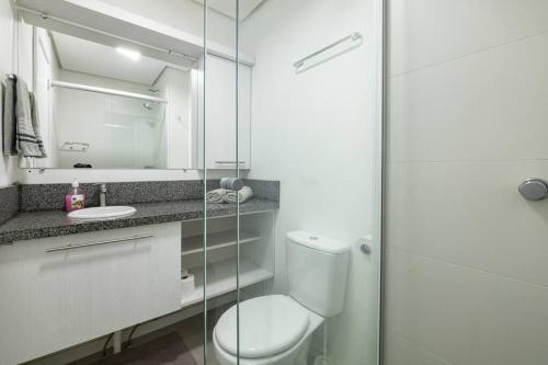 a bathroom with a toilet and a glass shower at Studio encantador no Parque Una com estacionamento incluído in Pelotas