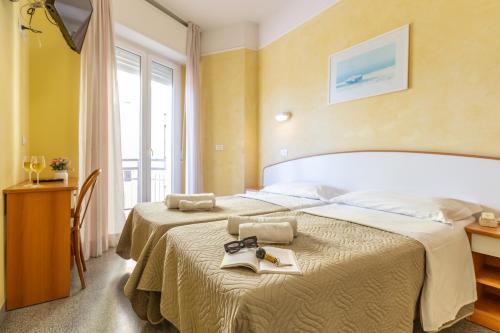 a hotel room with two beds and a window at Hotel Naica in Rimini