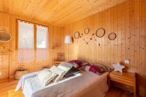 a bedroom with a bed in a wooden room at Chalet Les Tilleuls - Jolie vue montagne et lac in Les Angles